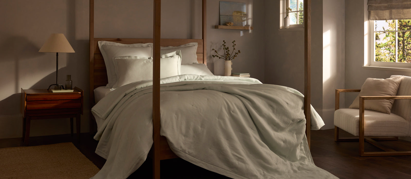 a four poster bed with Cozy Earth Linen bedding in a dimly lit, serene bedroom