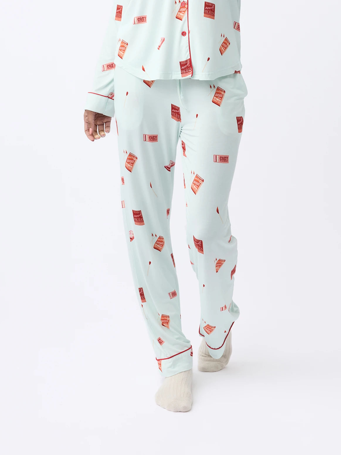 A person wearing Cozy Earth Women's Stretch-Knit Bamboo Pajama Pant in light blue with a red hot sauce bottle print and white socks, poses against a plain, light background.