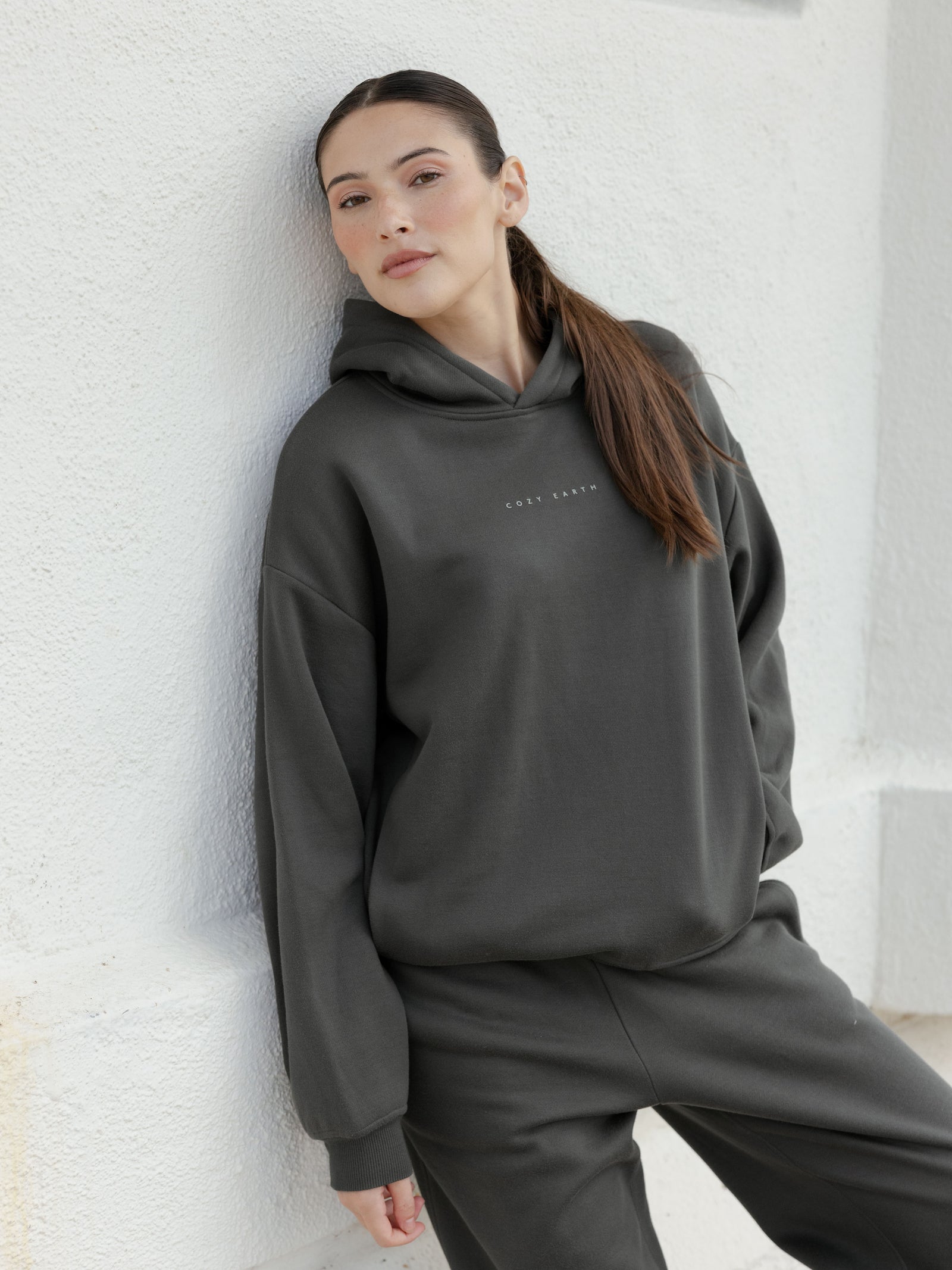 Woman in storm cityscape hoodie leaning against wall 