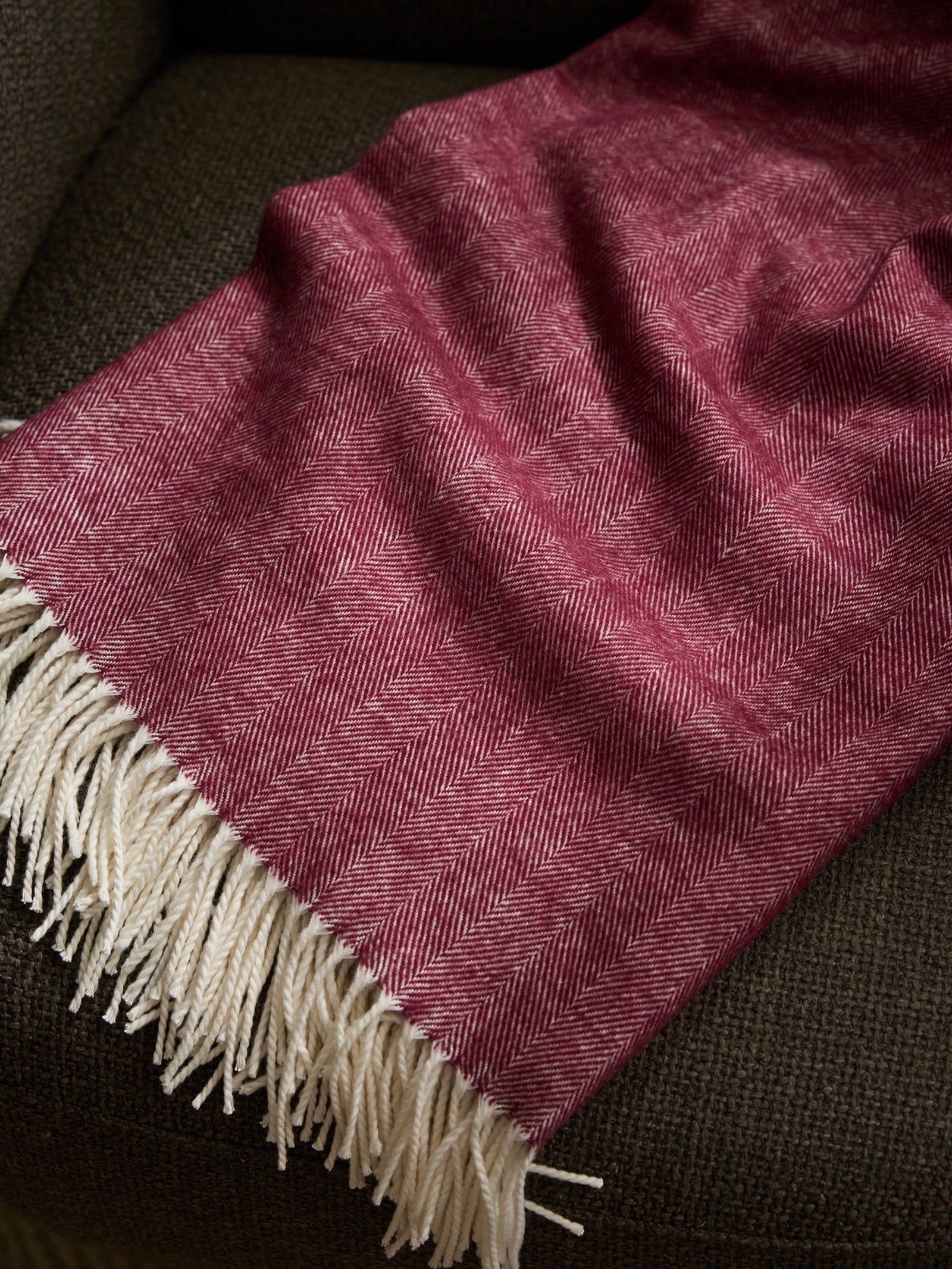 Berry herringbone tassel throw laying on sofa