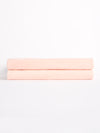 Two Luxe Bath Sheets by Cozy Earth, neatly folded and soft in pink, are stacked against a plain white backdrop. |Color:Blossom