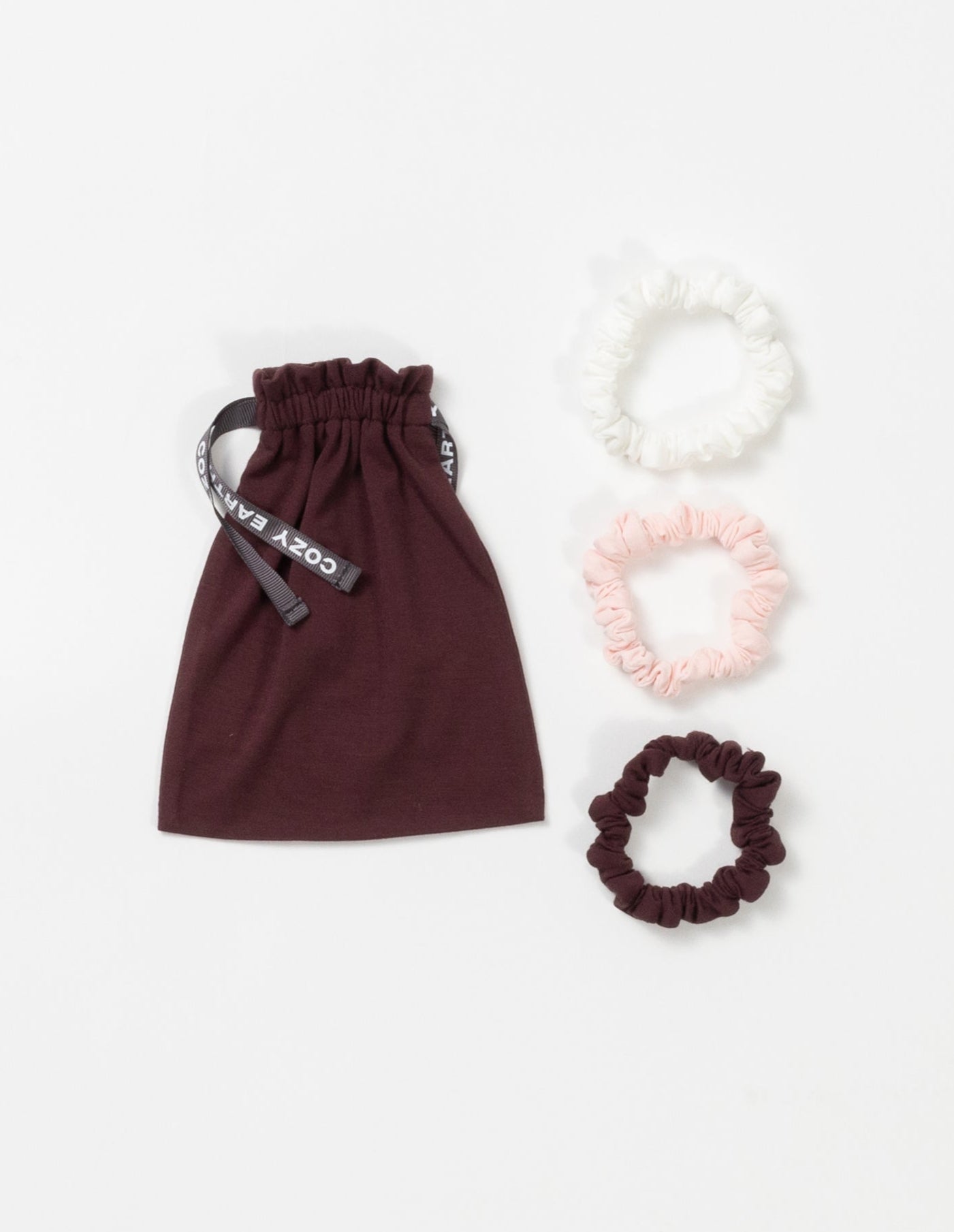 Cozy Earth Bamboo Stretch Knit Skinny Scrunchies in Ivory, Blossom, and Burgundy pictured with storage bag on a white background.