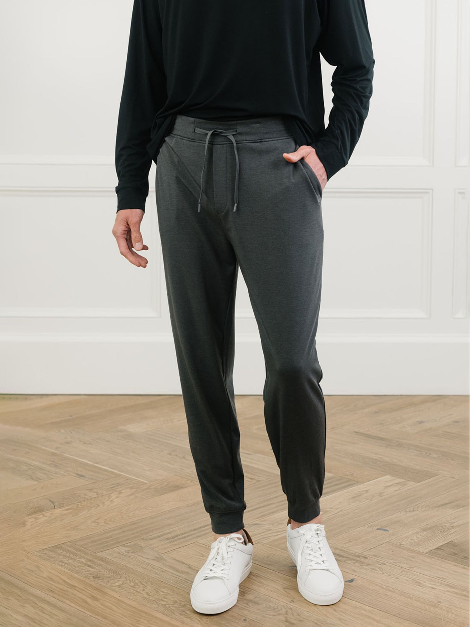 Charcoal/Black Men's Bamboo Jogger Set. There is a man wearing the jogger set. He is standing in a well lit room in a home. with his back to the camera.Color:Charcoal