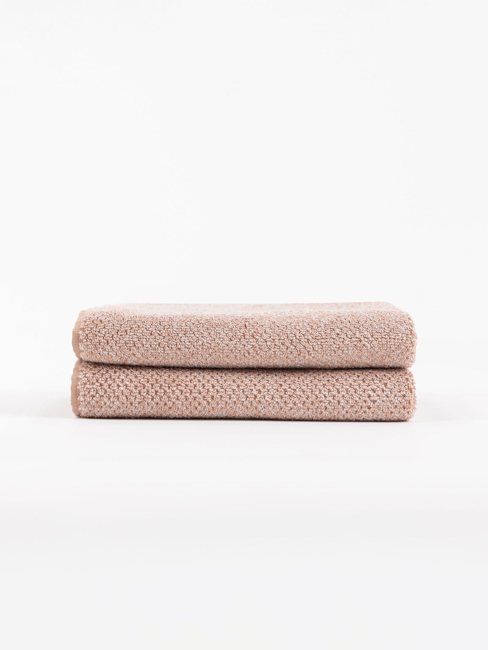 A pair of Nantucket Hand Towels in Heathered Clay is stacked in front of a white background.