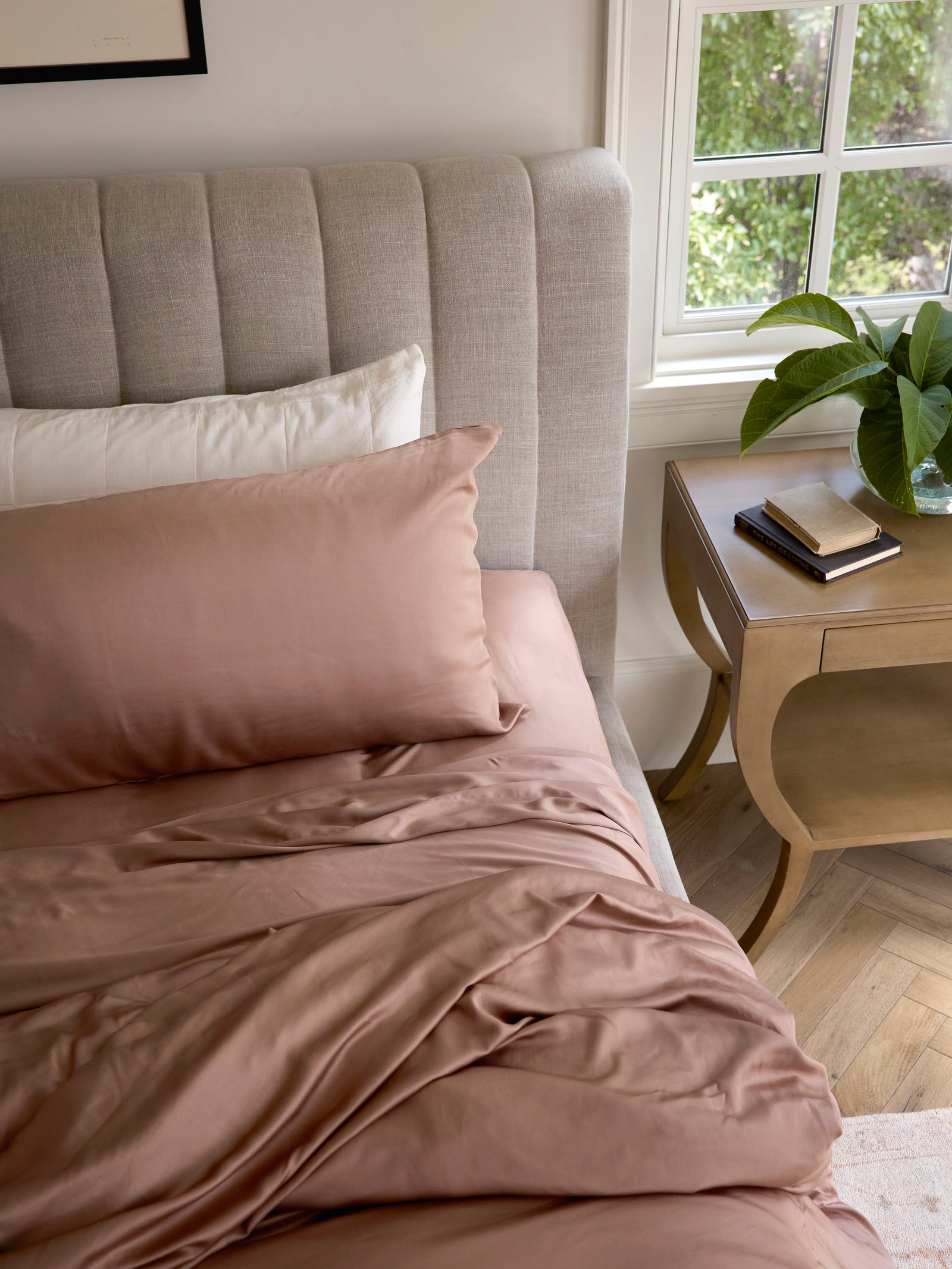 Clay bedding on unmade bed with books on the nightstand