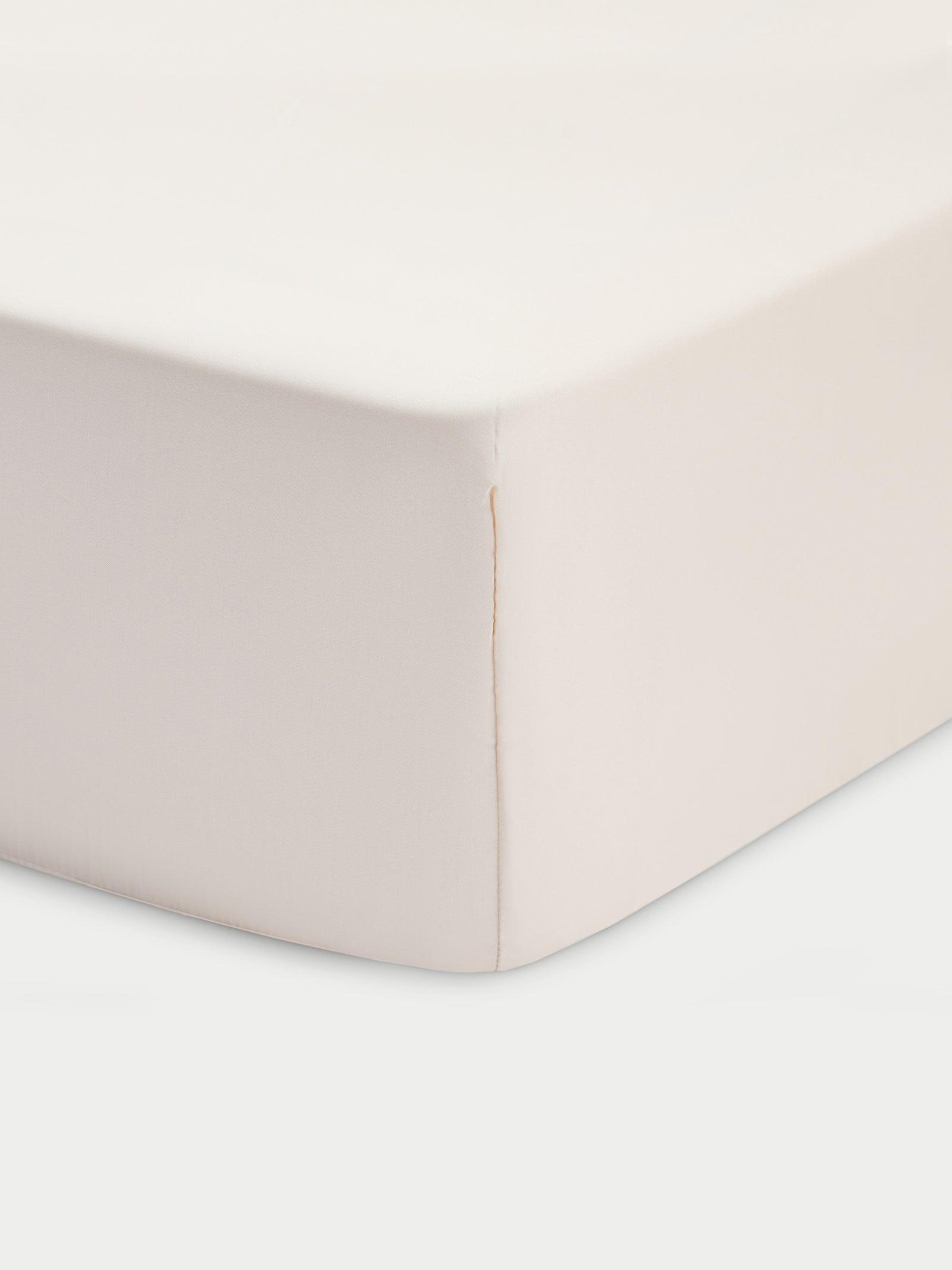 Corner of creme crib sheet with white baackground