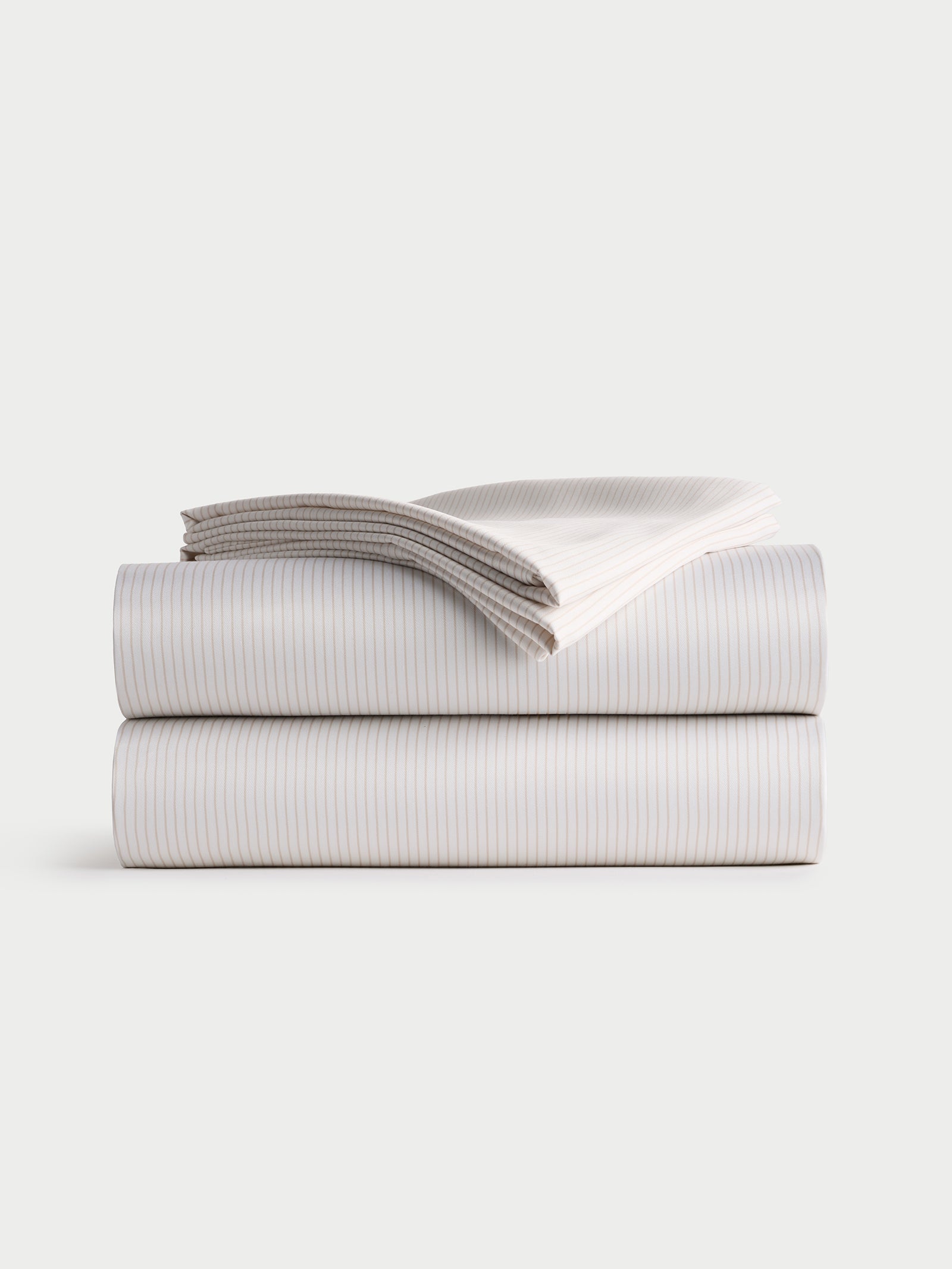 A neatly folded Bamboo Sheet Set by Cozy Earth, featuring a fitted sheet, flat sheet, and two pillowcases with a striped design, stacked on a plain white background.