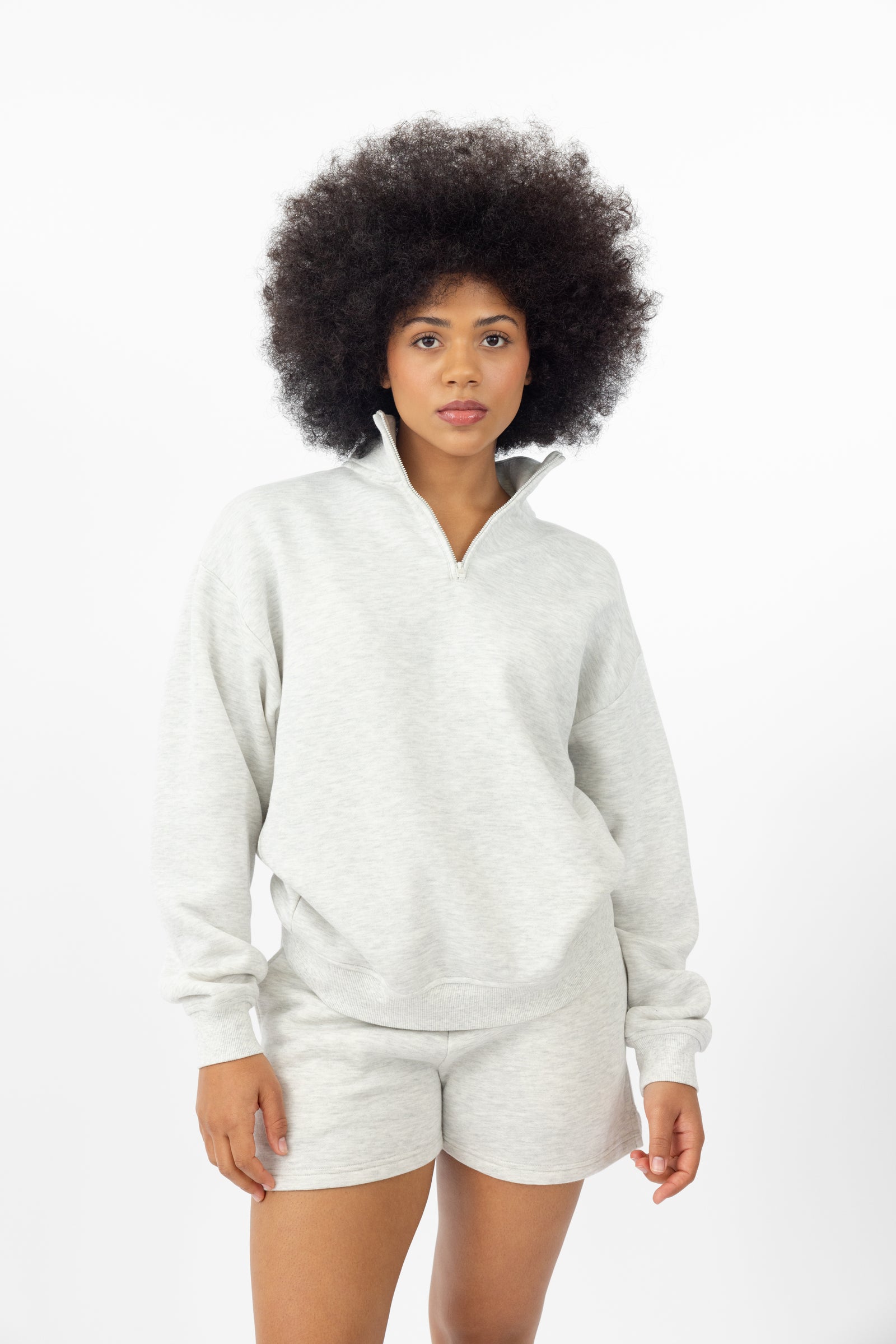 Heather Grey CityScape Quarter Zip. The quarter zip is being worn by a female model. The model is wearing accompanying CityScape clothing to complete the look of the quarter zip. The photo was taken with a white background.