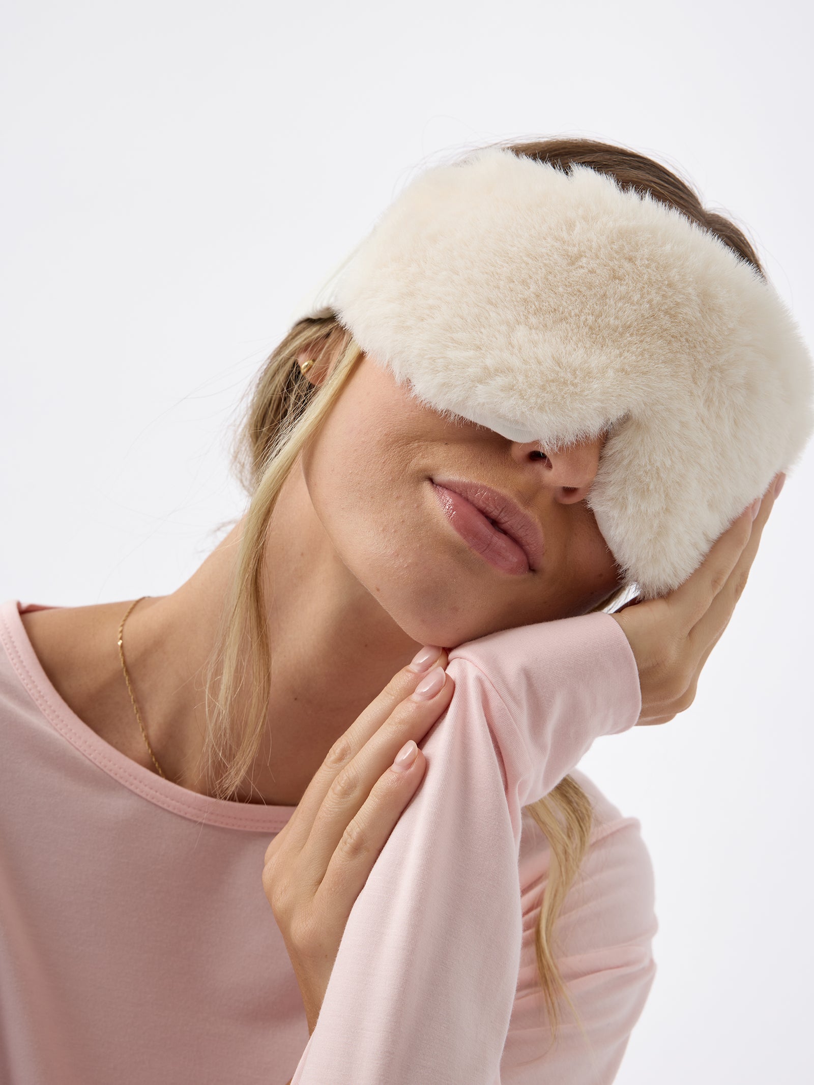 A woman wears the Cozy Earth Faux Fur Sleep Mask in Ivory.