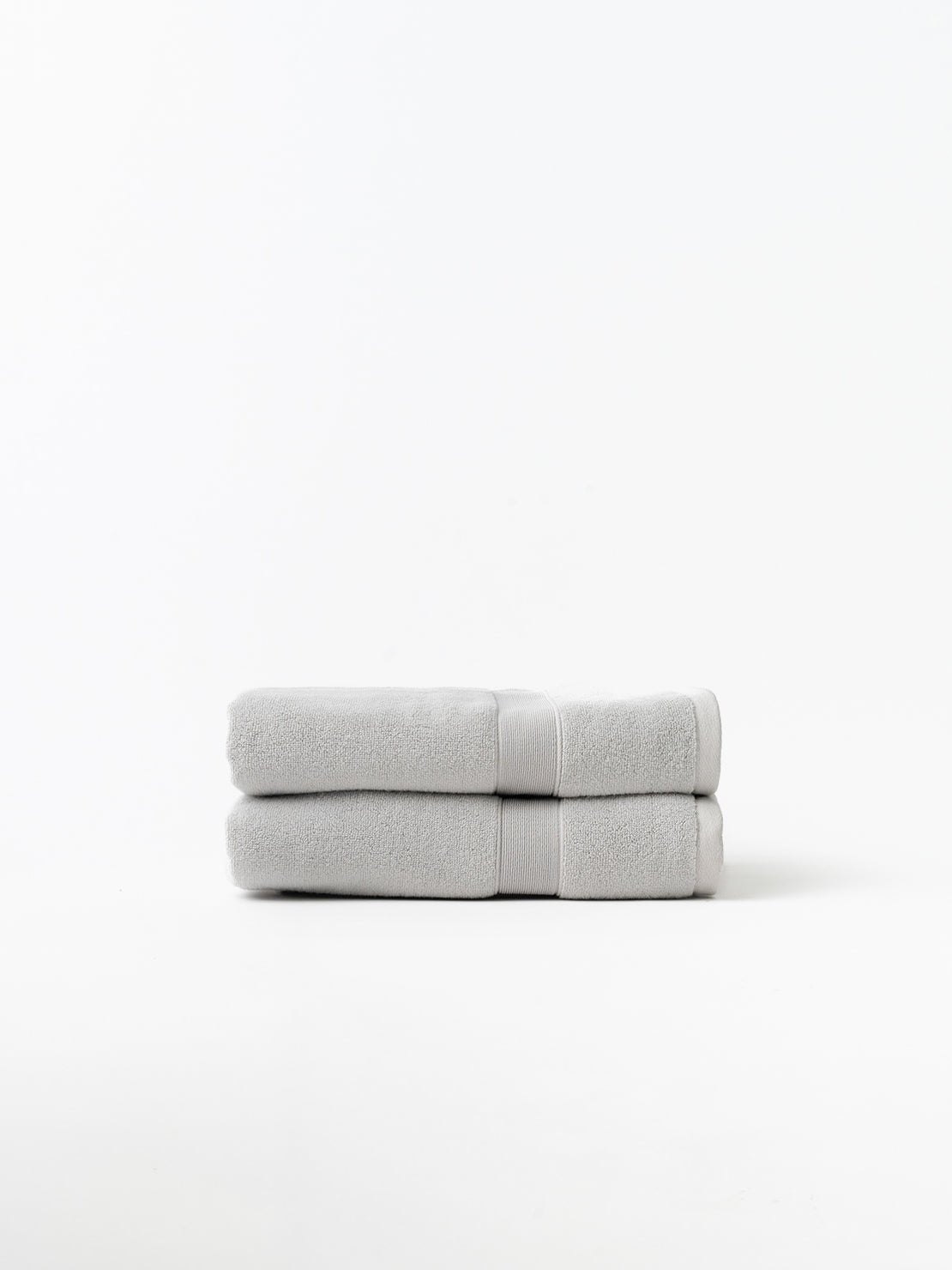Light grey luxe bath towels folded with white background 
