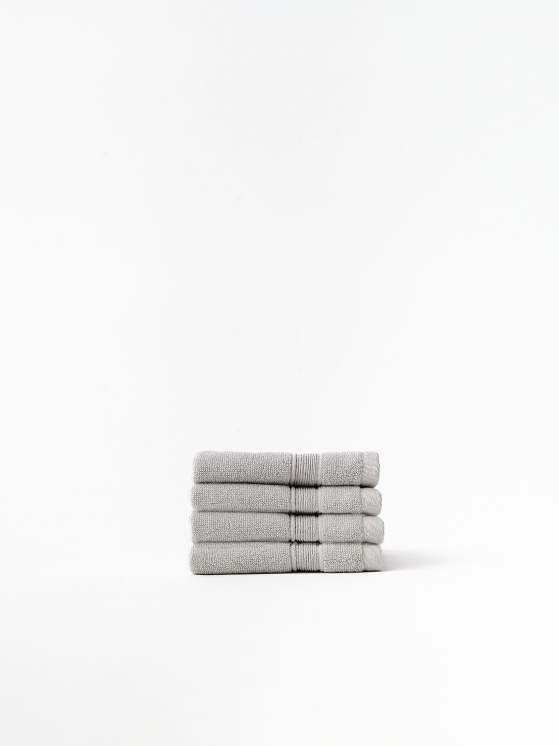 Light grey washcloths folded with white background 