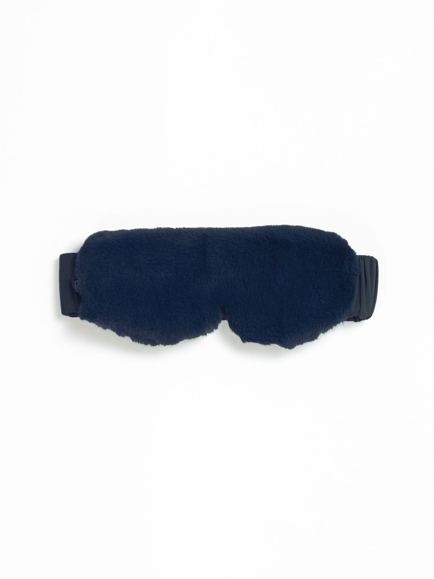 The Cozy Earth Faux Fur Sleep Mask, in fluffy dark blue with an adjustable black strap, is set against a plain white background.