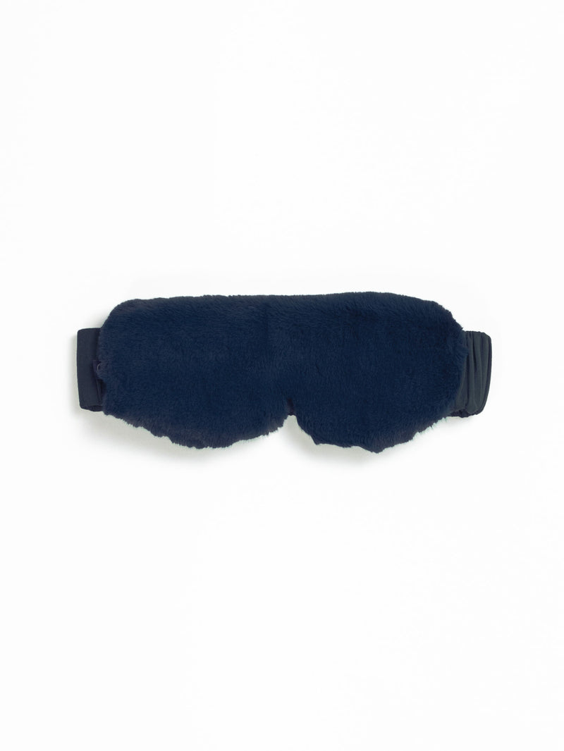 The Cozy Earth Faux Fur Sleep Mask, in fluffy dark blue with an adjustable black strap, is set against a plain white background.