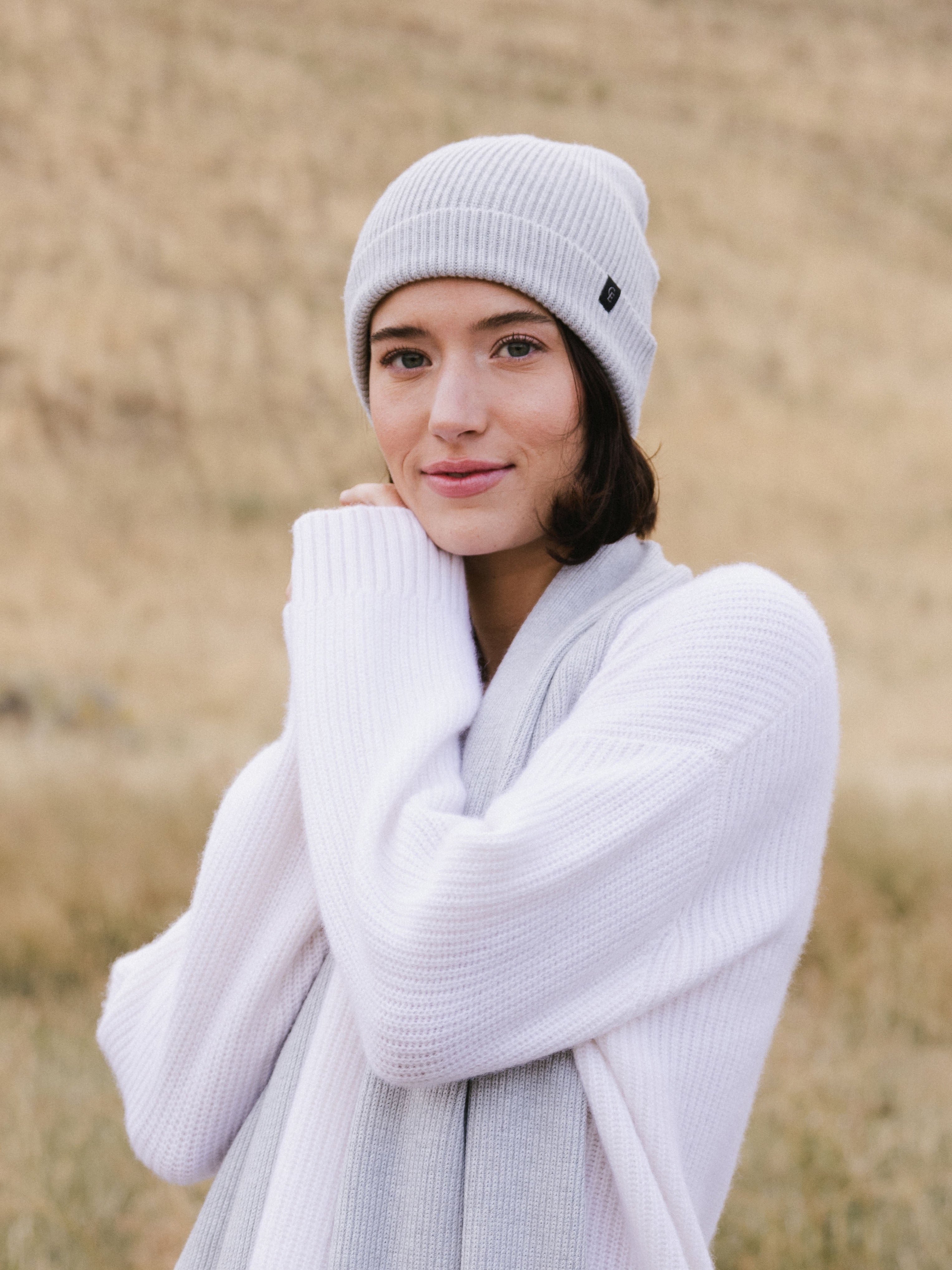 Woman wearing a light gray knit beanie and scarf in a field |Color:Light Grey