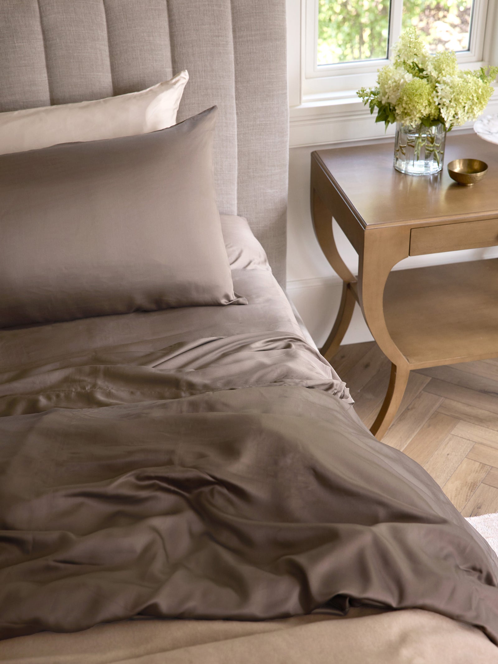 Walnut bedding with a wooden night stand to the side 