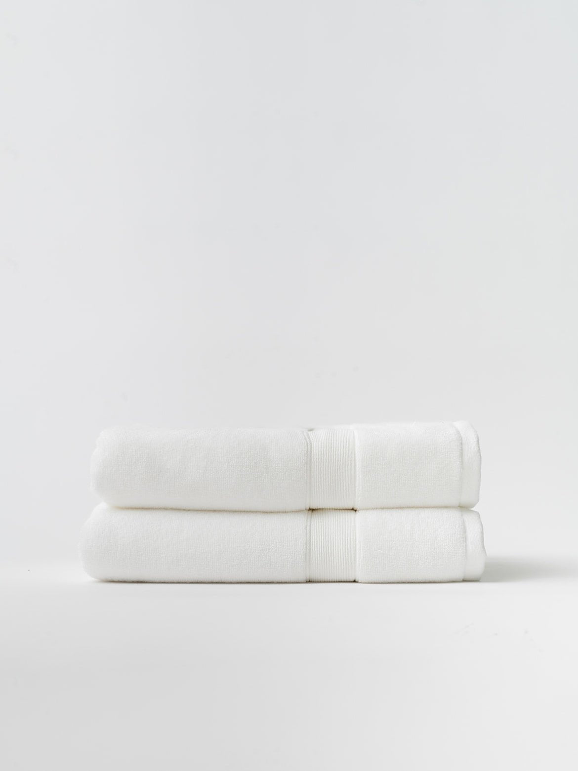 White luxe bath towels folded with white background 