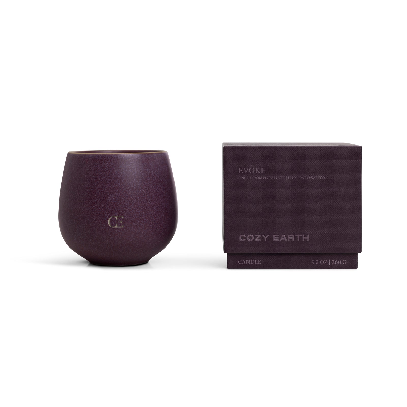 A deep purple Cozy Earth Candle EVOKE in a rounded cup with "CE" embossed on the front sits beside a matching purple box labeled "Evoke." Size: 9.2 oz (260 g).