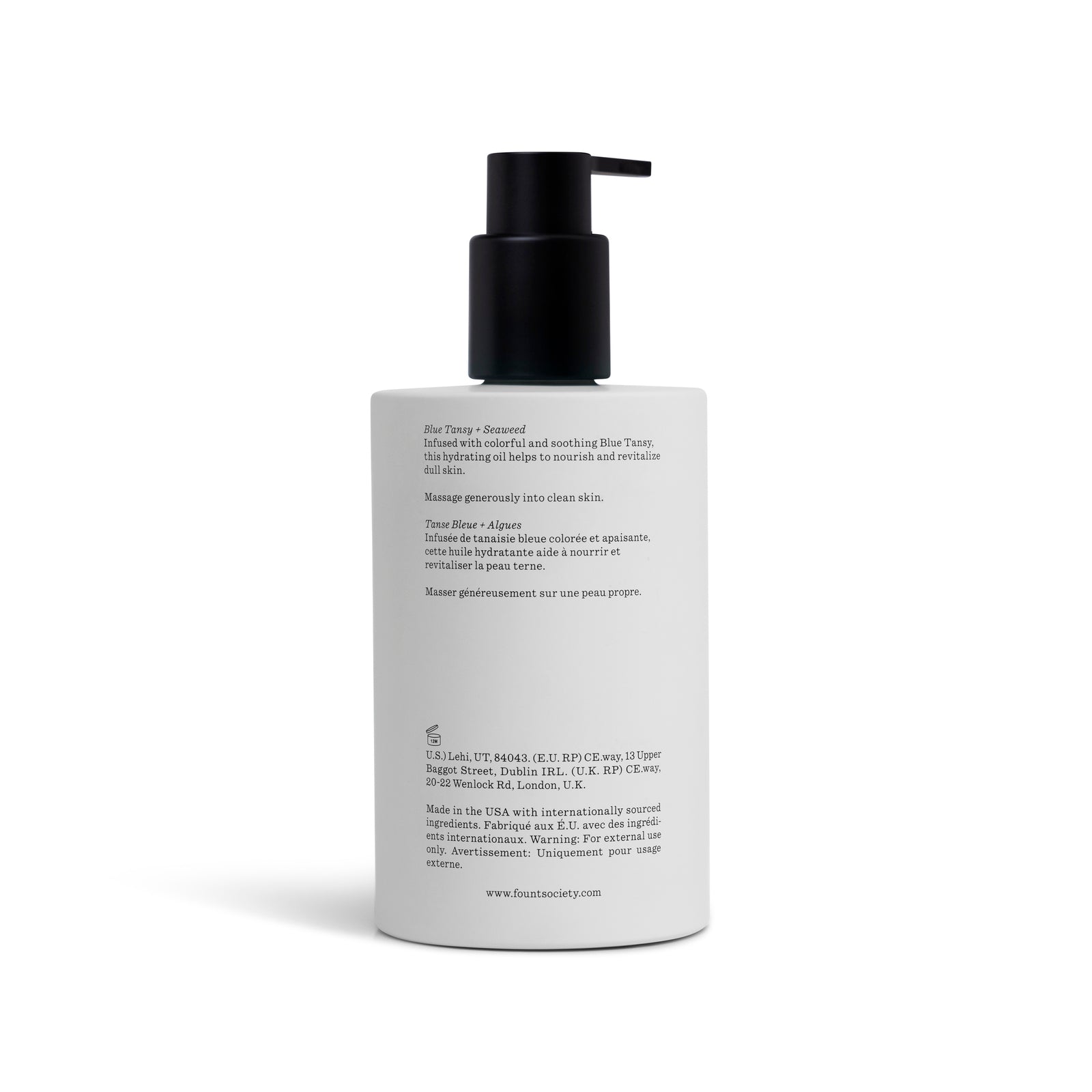 A white bottle of Cozy Earth Body Oil with a black pump and black text detailing product info, ingredients, and origin. The upright bottle stands on a white background.