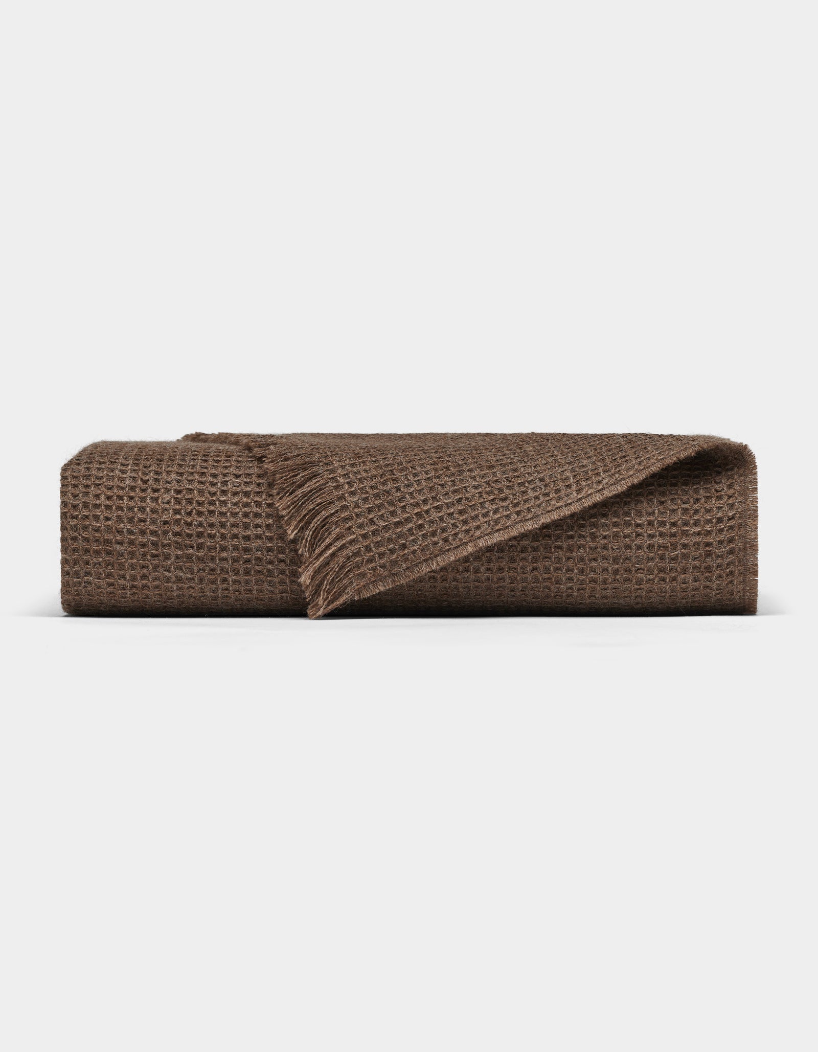 The Cozy Earth Alpaca Waffle Throw features a brown textured waffle weave and fringed edges, shown folded against a plain white background.