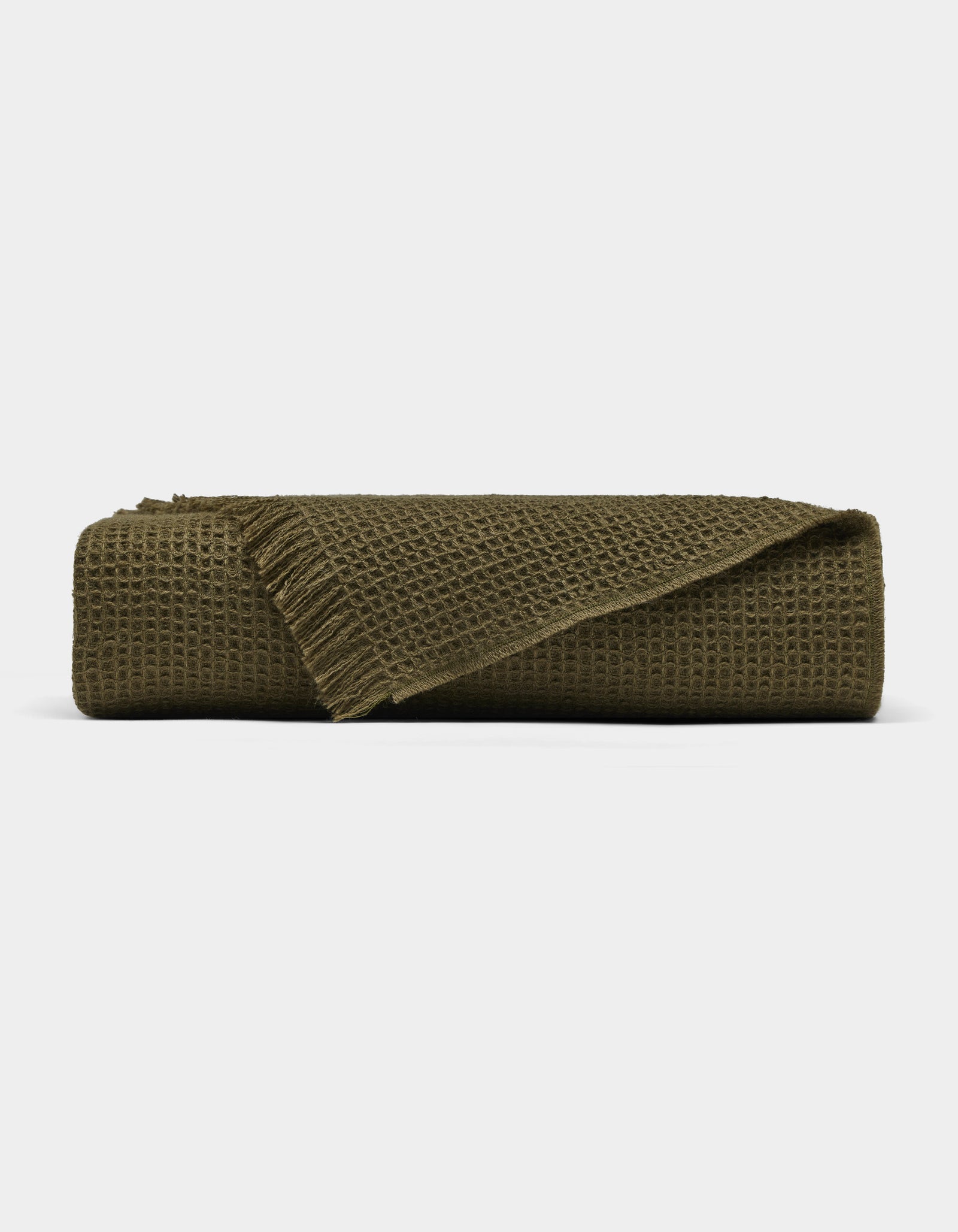 The Cozy Earth Alpaca Waffle Throw, in dark olive green with a waffle texture and fringed edges, is shown folded against a plain white background.