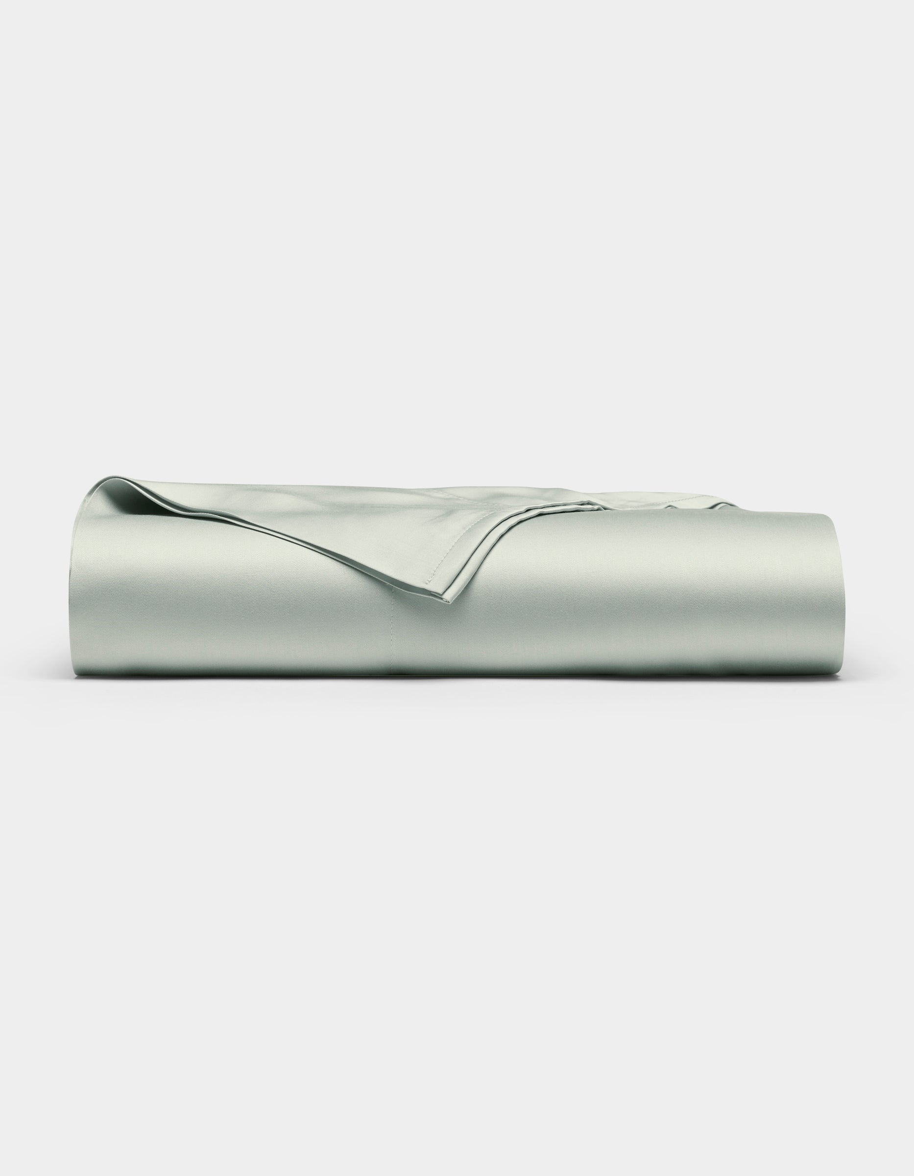 A neatly folded Bamboo Flat Sheet by Cozy Earth in light gray is displayed against a plain white background.|Color:Laurel