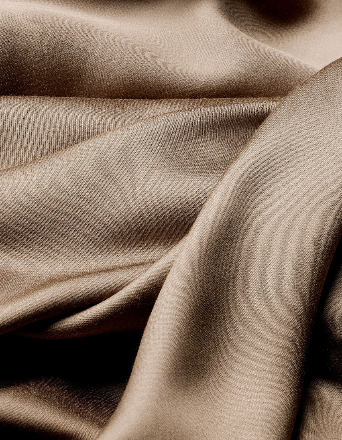 The Cozy Earth Bamboo Flat Sheet features smooth, light brown satin fabric with soft folds and gentle curves for a shimmering, luxurious texture.
