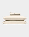 The Cozy Earth Bamboo Sheet Set, neatly folded in cream, rests atop two matching pillows against a light gray background.|Color:Creme