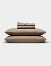 A neatly folded Cozy Earth Bamboo Sheet Set in taupe, with pillowcases, is stacked atop two matching pillows against a plain white background.|Color:Walnut
