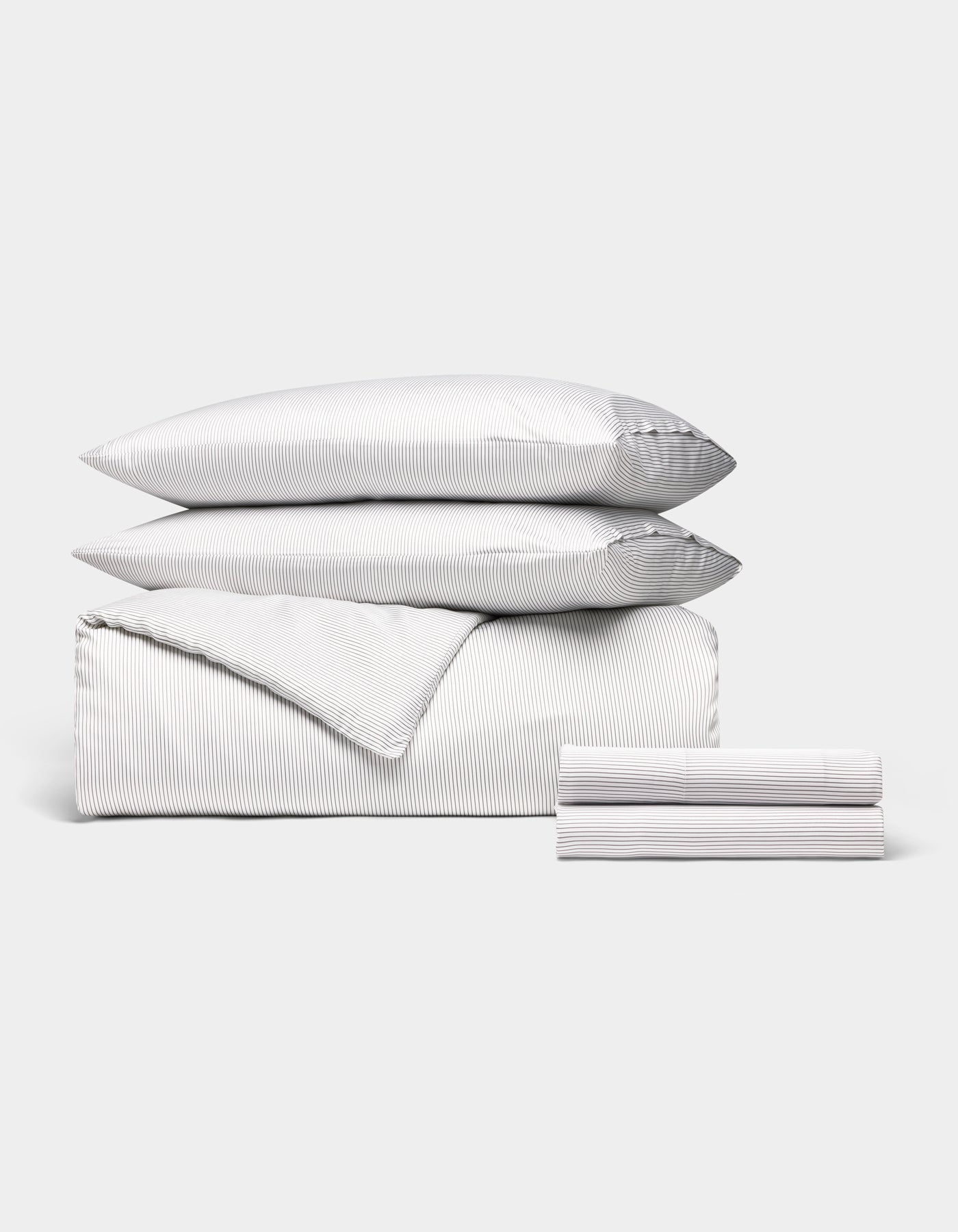 The Cozy Earth Bamboo Bedding Deluxe Bundle features a neatly arranged set with thin gray and white stripes, including two pillows, a folded comforter, and stacked sheets—all displayed against a plain white background.