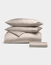 The Cozy Earth Bamboo Bedding Essential Bundle includes two pillows, a folded duvet, and a folded sheet in beige, all neatly stacked against a plain white background.|Color:Driftwood