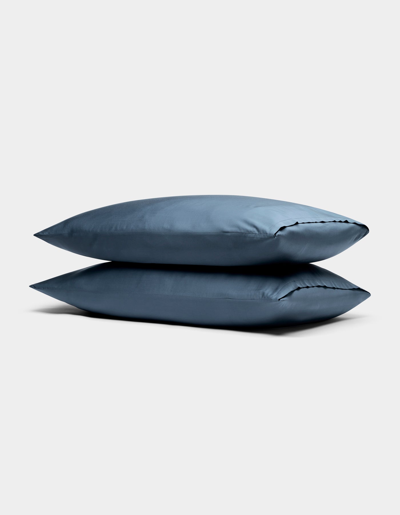 Two Cozy Earth Bamboo Pillowcases in blue are stacked against a plain, light gray background.