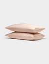 Two light pink Cozy Earth Bamboo Pillowcases are stacked neatly atop each other against a plain, light gray background.|Color:Peony