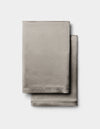 Two neatly folded Cozy Earth Silk Pillowcases in light gray are stacked together against a plain white background.|Color:Charcoal