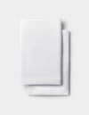 A neatly folded white Silk Pillowcase by Cozy Earth is stacked on a light gray background.|Color:White