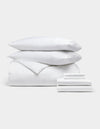 The Cozy Earth Bamboo Bedding Ultimate Bundle, featuring two pillows stacked on a comforter and folded sheets, is neatly displayed against a plain light gray background.|Color:White