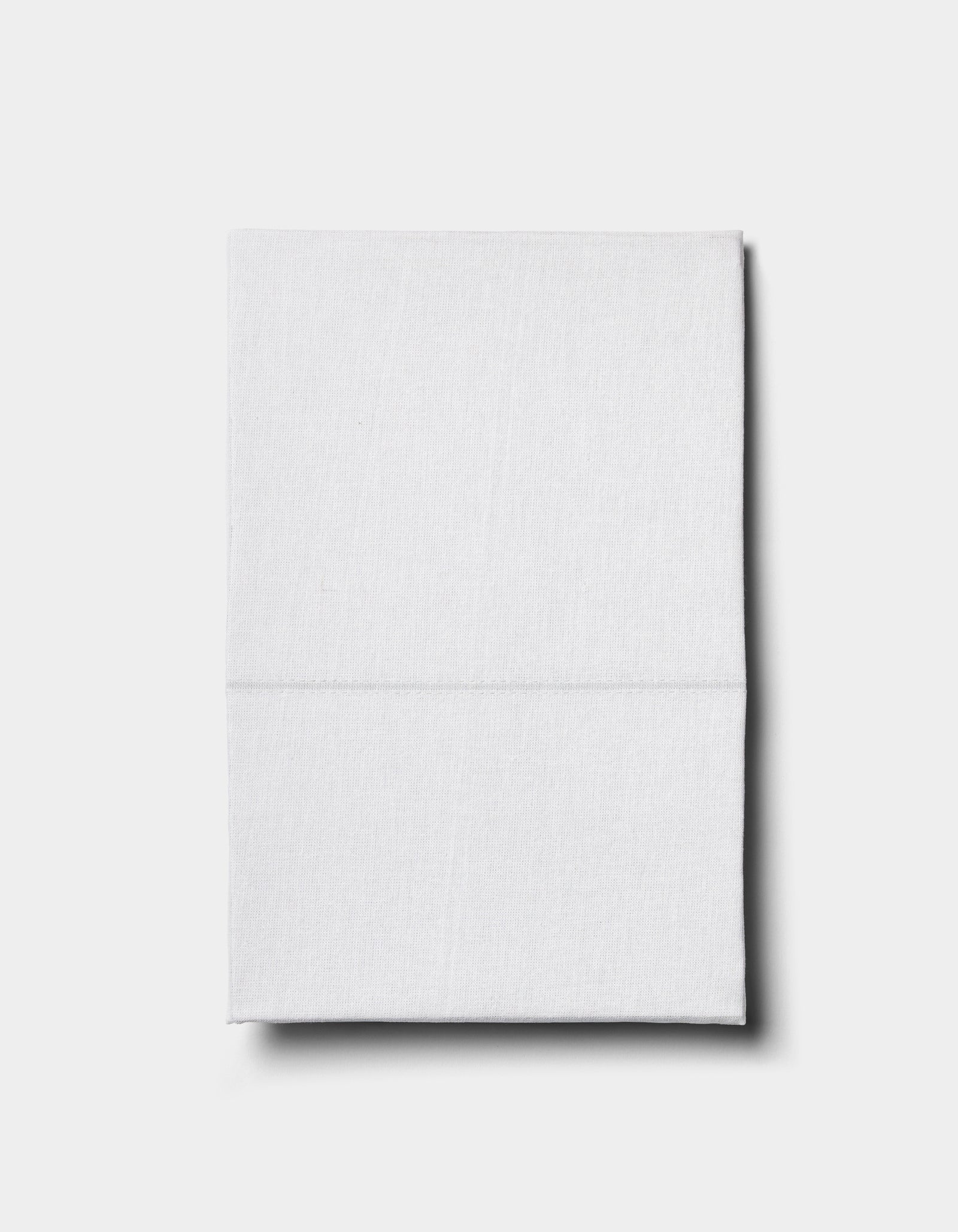 The Baja Double Sided Sham by Cozy Earth, neatly folded, rests on a plain light gray surface and casts a subtle shadow to the right.