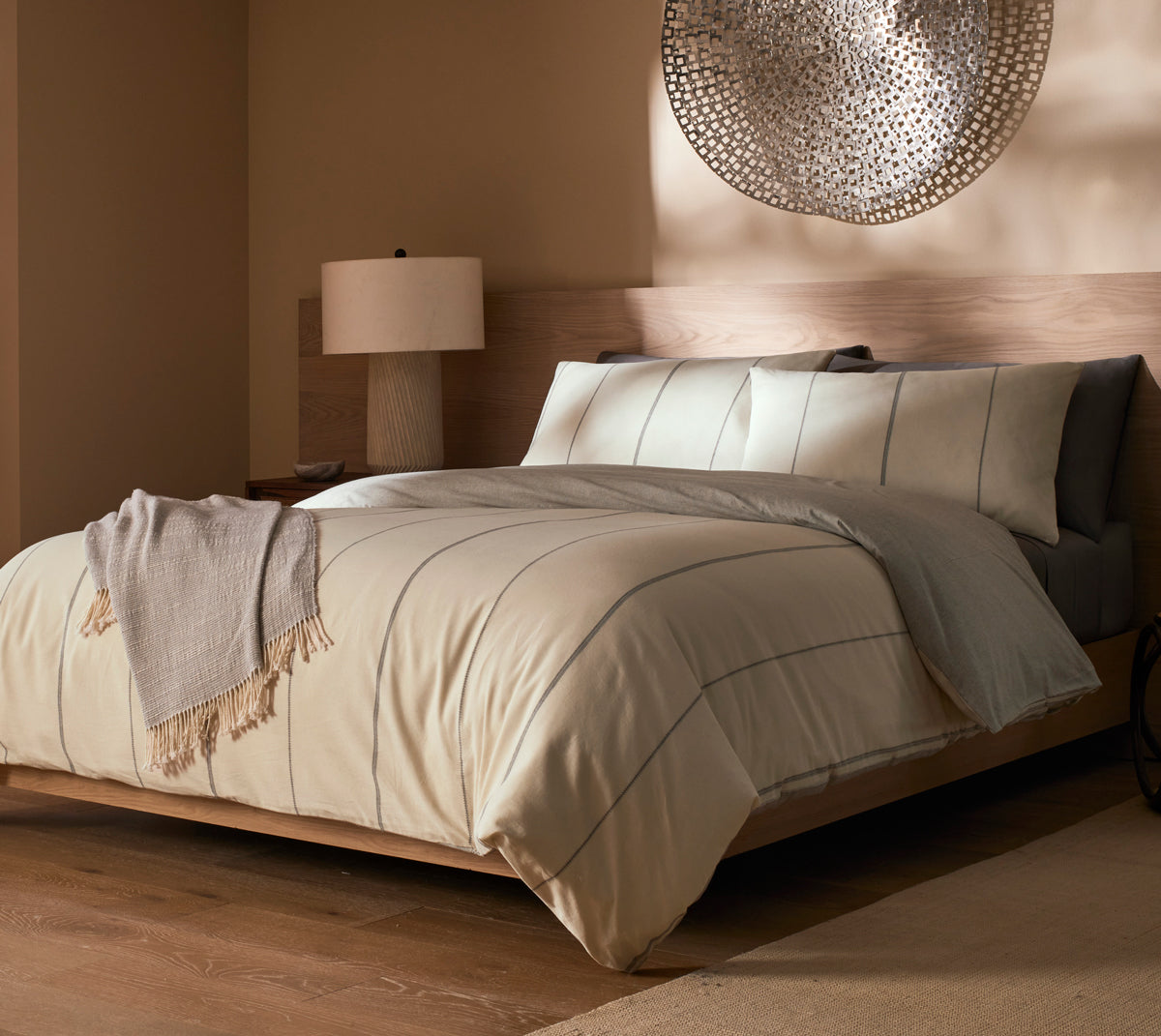 Neatly made bed with Cozy Earth Baja bedding in a bedroom setting.