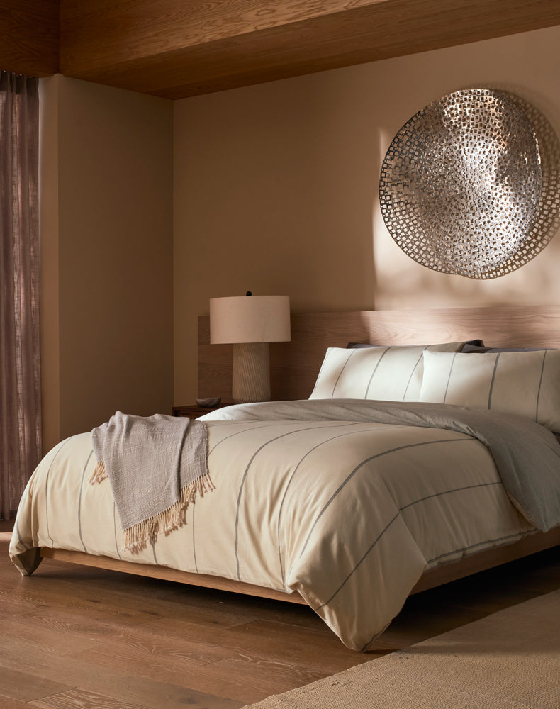Neatly made bed in a bedroom with a decorative wall piece.