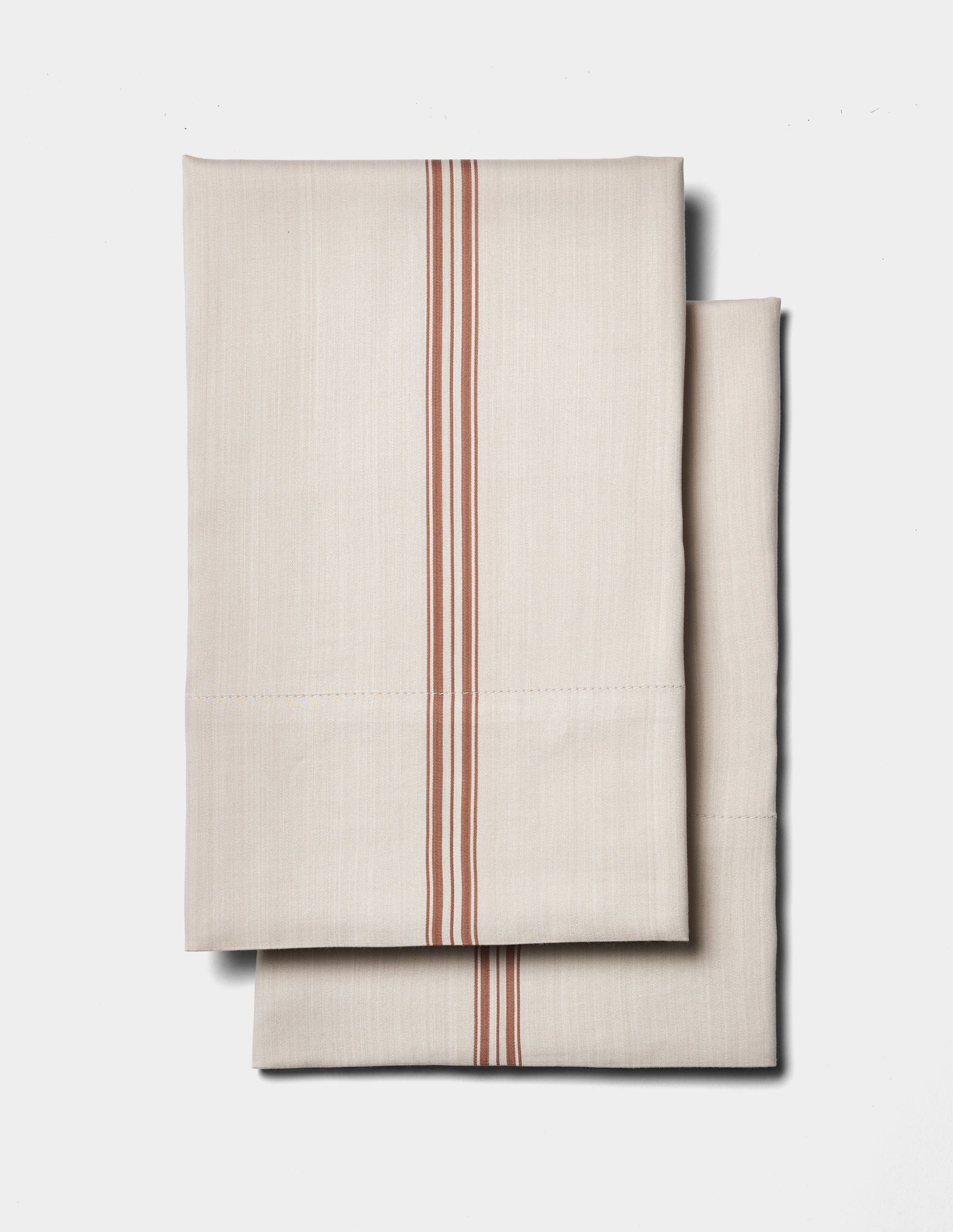 Two folded Cozy Earth Bamboo Pillowcases in beige with vertical red stripes are displayed on a plain white background.