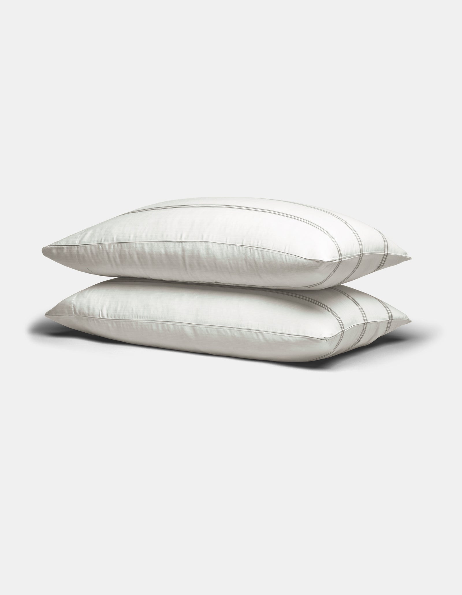 Two Cozy Earth Bamboo Pillowcases in white with subtle gray stripes are stacked on a plain light gray background.