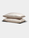 Two Cozy Earth Bamboo Pillowcases in cream with subtle brown stripes are stacked neatly on a plain light gray background.|Color:Baja Stripe in Maple