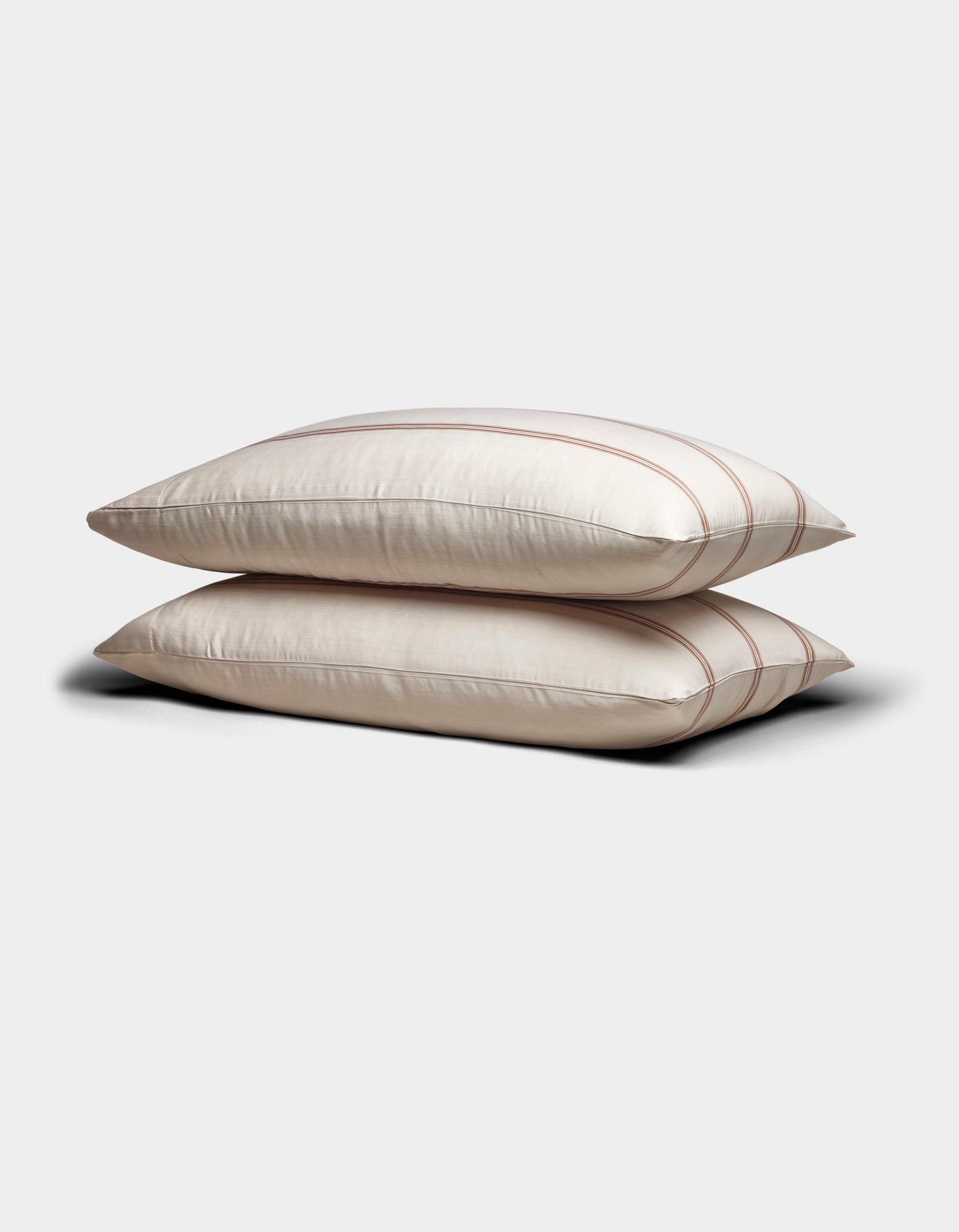 Two Cozy Earth Bamboo Pillowcases in cream with subtle brown stripes are stacked neatly on a plain light gray background.
