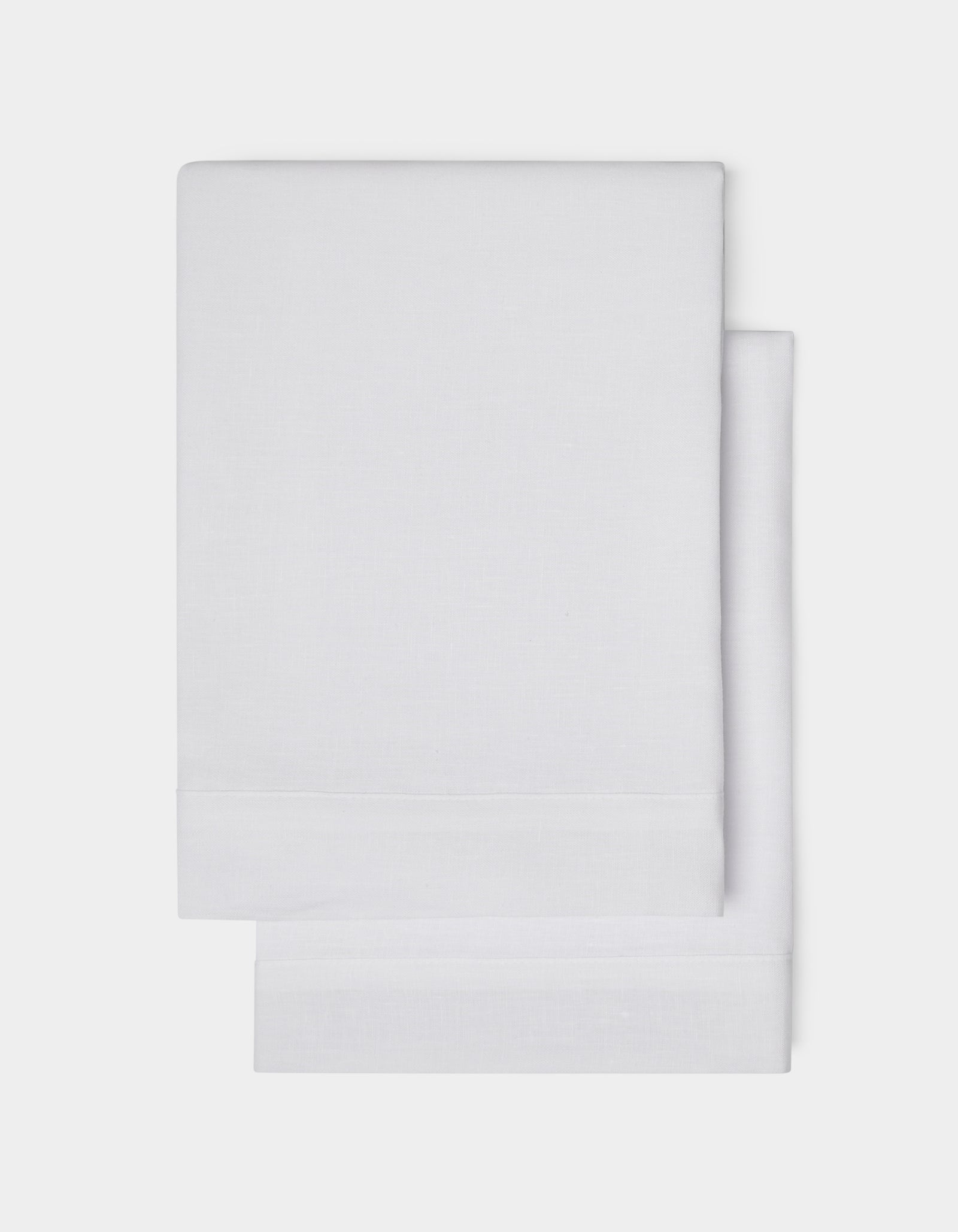 Cozy Earth Linen Shams, neatly folded in plain white with a simple hemmed edge, are shown on a white background.