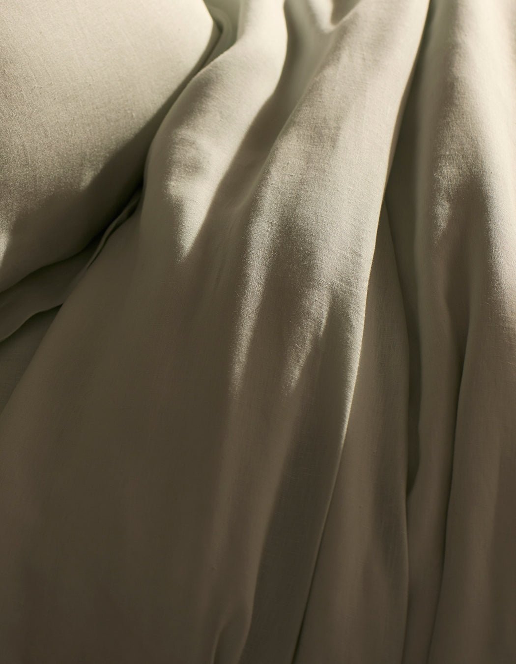 A close-up of Cozy Earth’s Linen Duvet Cover shows soft, beige fabric with gentle folds and a smooth, slightly wrinkled texture, creating a calm and cozy atmosphere—perfect for a relaxing bedroom.