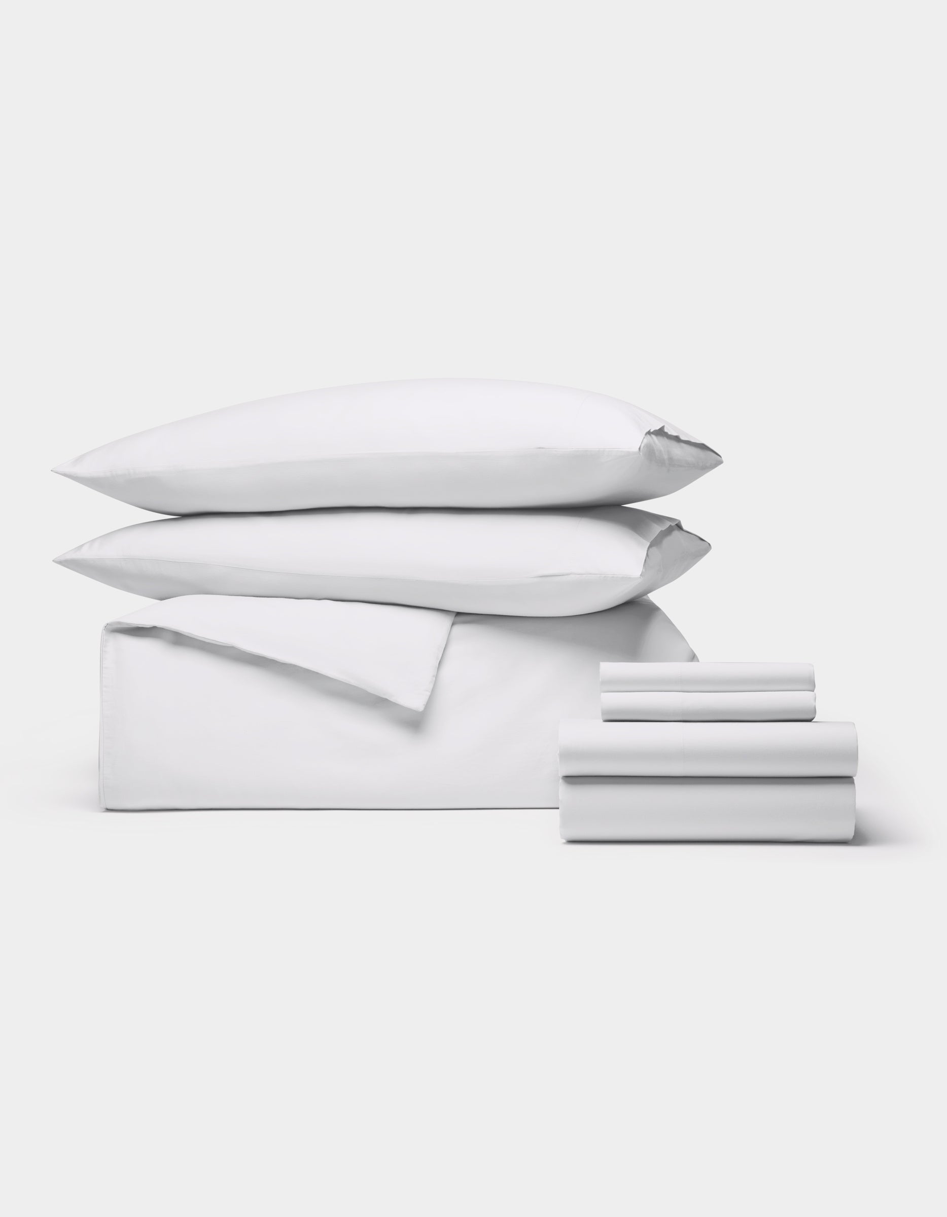 The Cozy Earth Soft-Wash Cotton Bedding Core Bundle features two pillows, a folded duvet, and several neatly stacked sheets, all displayed against a plain white background.|Color:White