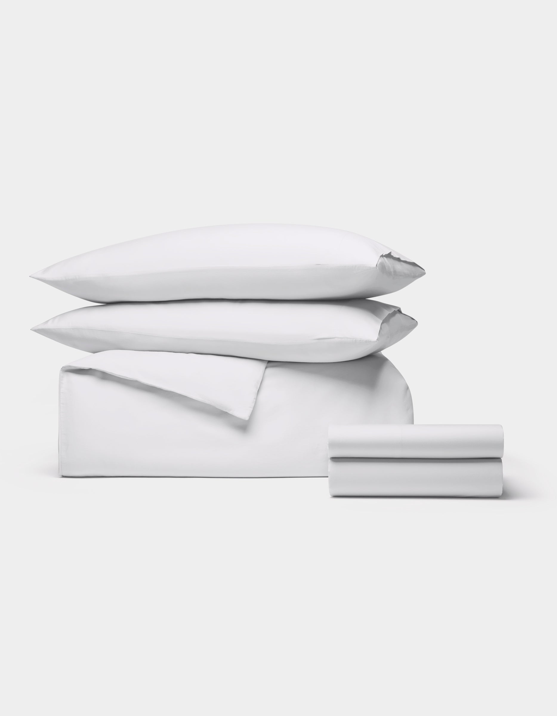 The Cozy Earth Soft-Wash Cotton Bedding Deluxe Bundle, featuring two pillows, a duvet cover, and two sheets in white, is neatly stacked against a plain light gray background.|Color:White