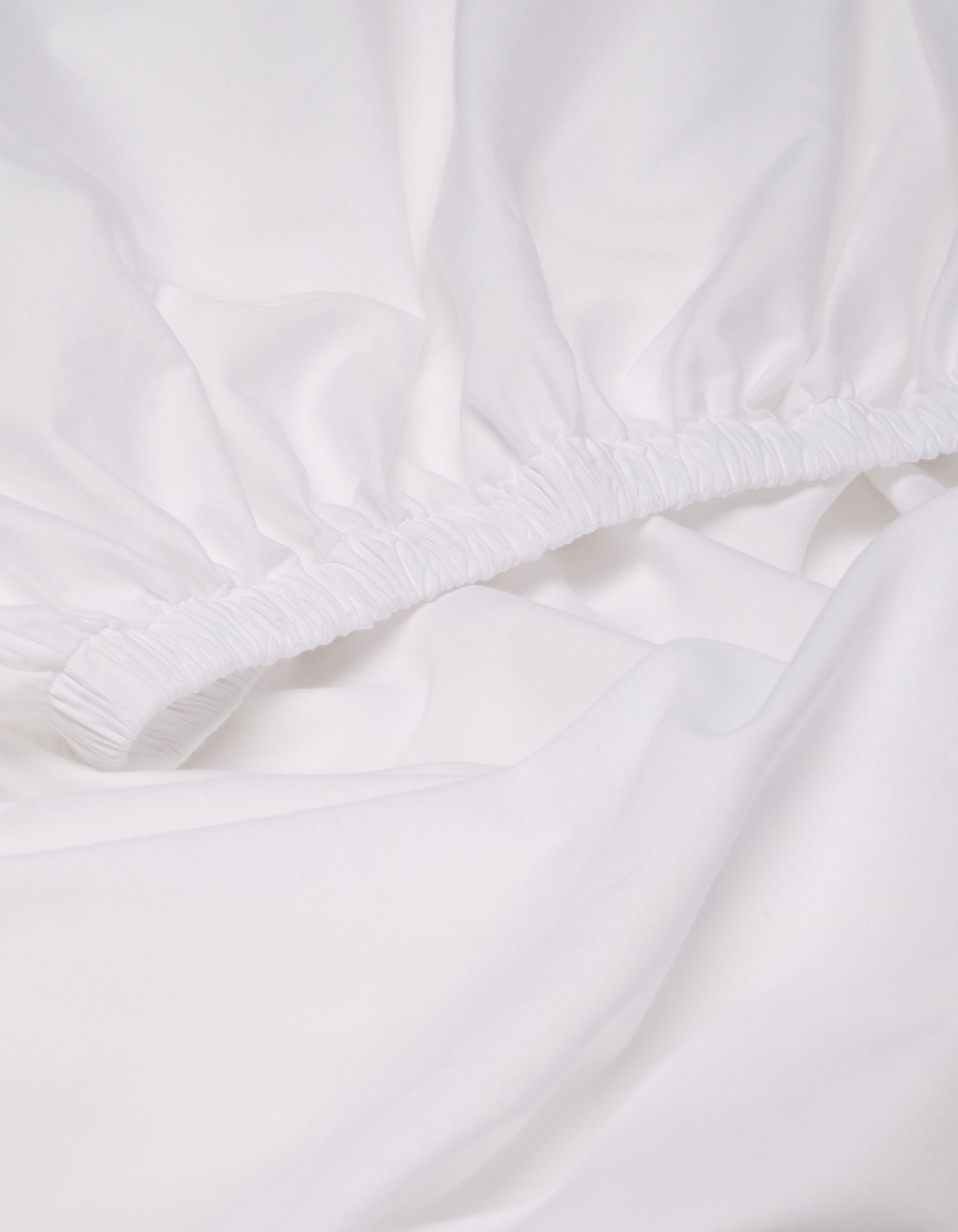 Close-up of the Cozy Earth Soft-Wash Cotton Fitted Sheet, featuring elastic edges, gathered fabric, and a smooth surface.