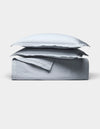 The Cozy Earth Soft-Wash Cotton Quilt Bundle, featuring two pillows and a folded light gray sheet, is neatly stacked and displayed against a plain white background.|Color:Shore