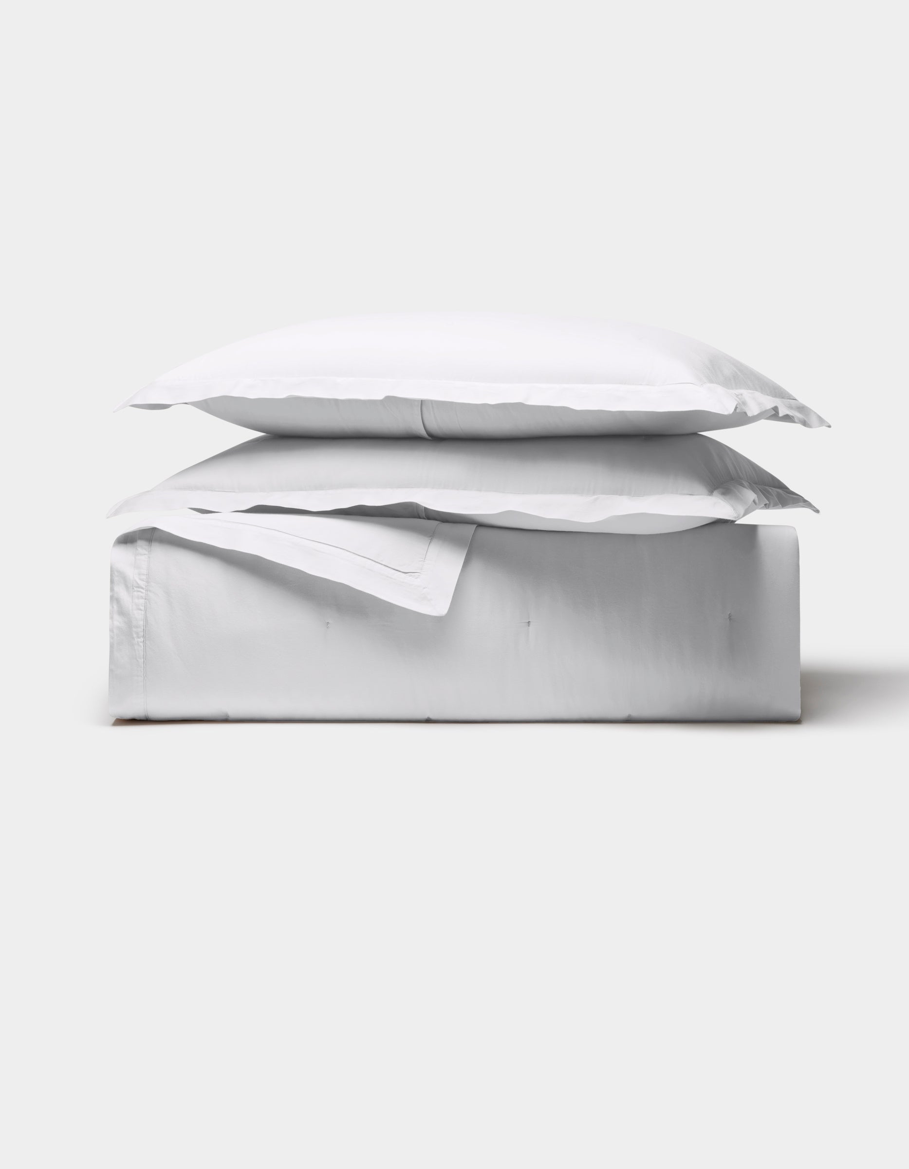The Cozy Earth Soft-Wash Cotton Quilt Bundle is neatly folded with a pillow on top, showcased against a plain light gray background.|Color:White