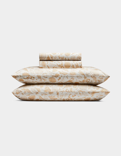 The Cozy Earth Bamboo Sheet Set includes two pillows and folded sheets with an intricate gold floral botanical pattern on a white background.|Color:Winter Toile Dijon